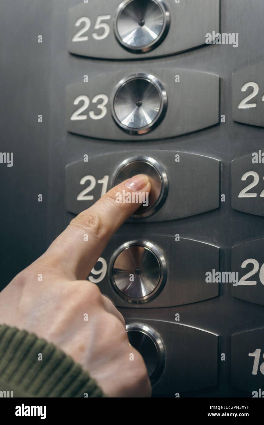Finger on lift button. Woman touching elevator button. Choice of level in elevator. Panel of floor numbers. Modern elevator interior. Stock Photo