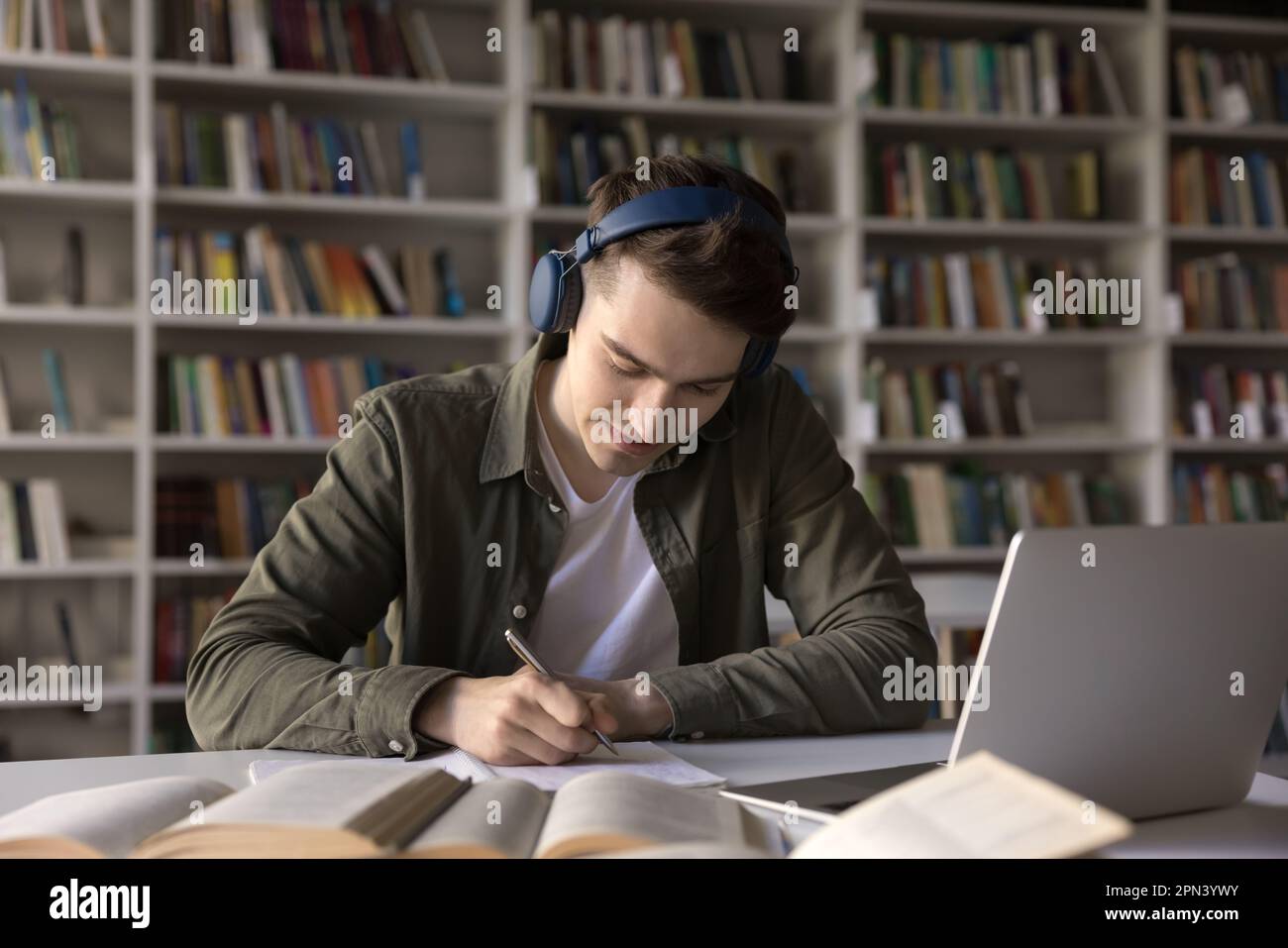 Schoolboy listening task through headphones prepare assignment sit in library Stock Photo