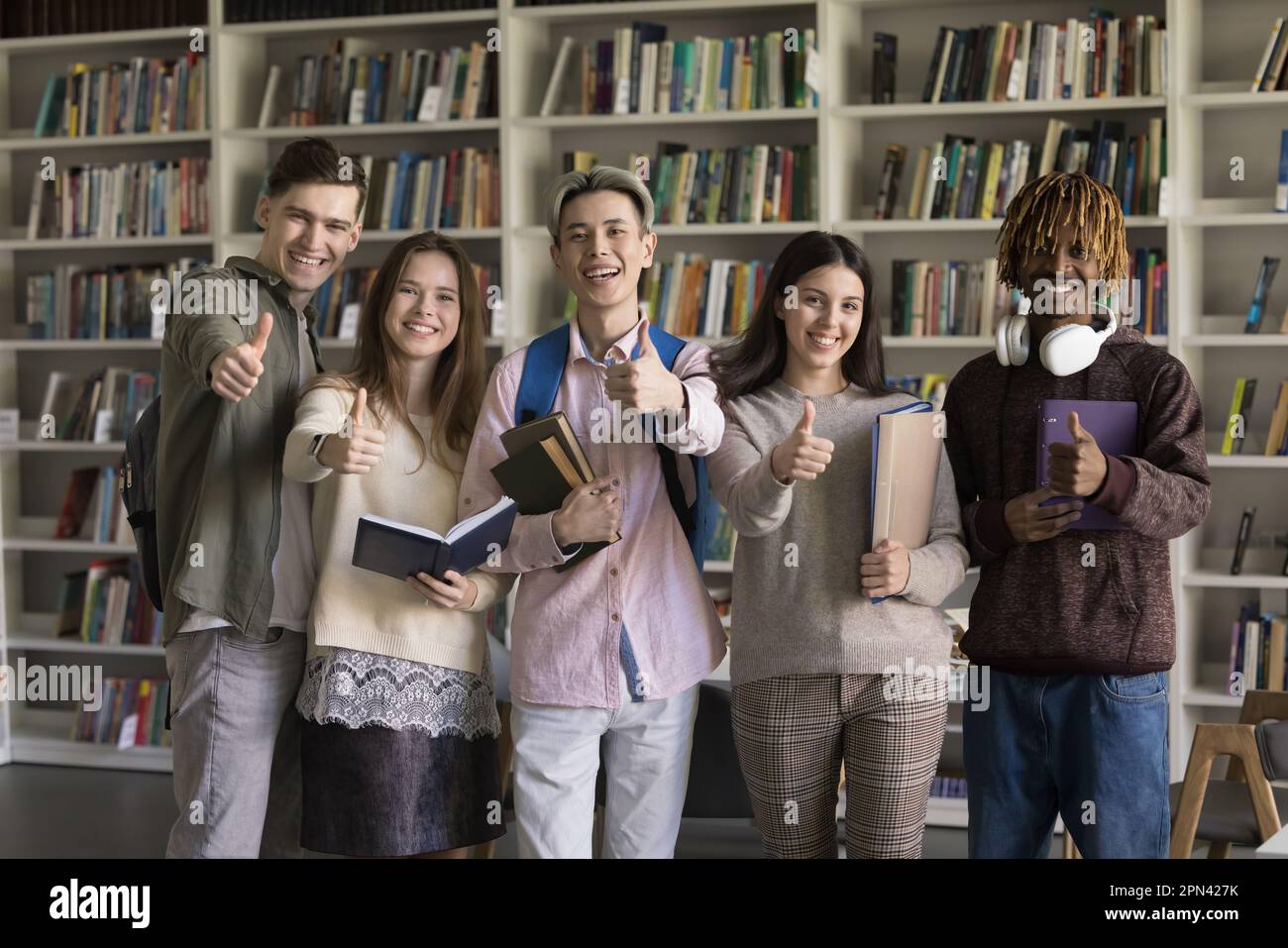 Group of multiracial students showing thumb up gesture in library Stock ...