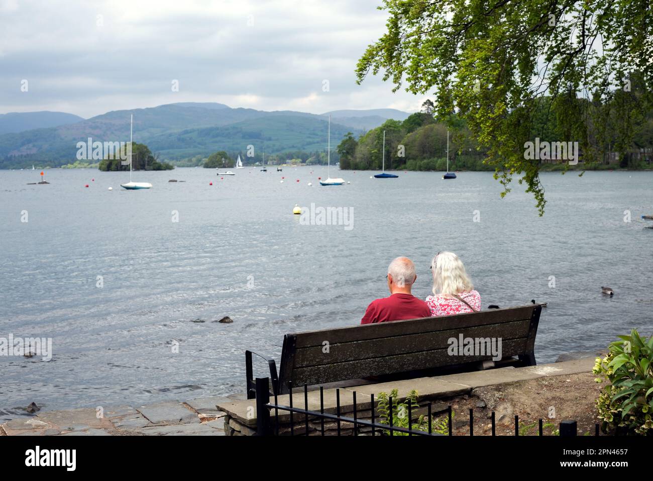 Elderly couple sitting on a bench by the lake Stock Photo - Alamy