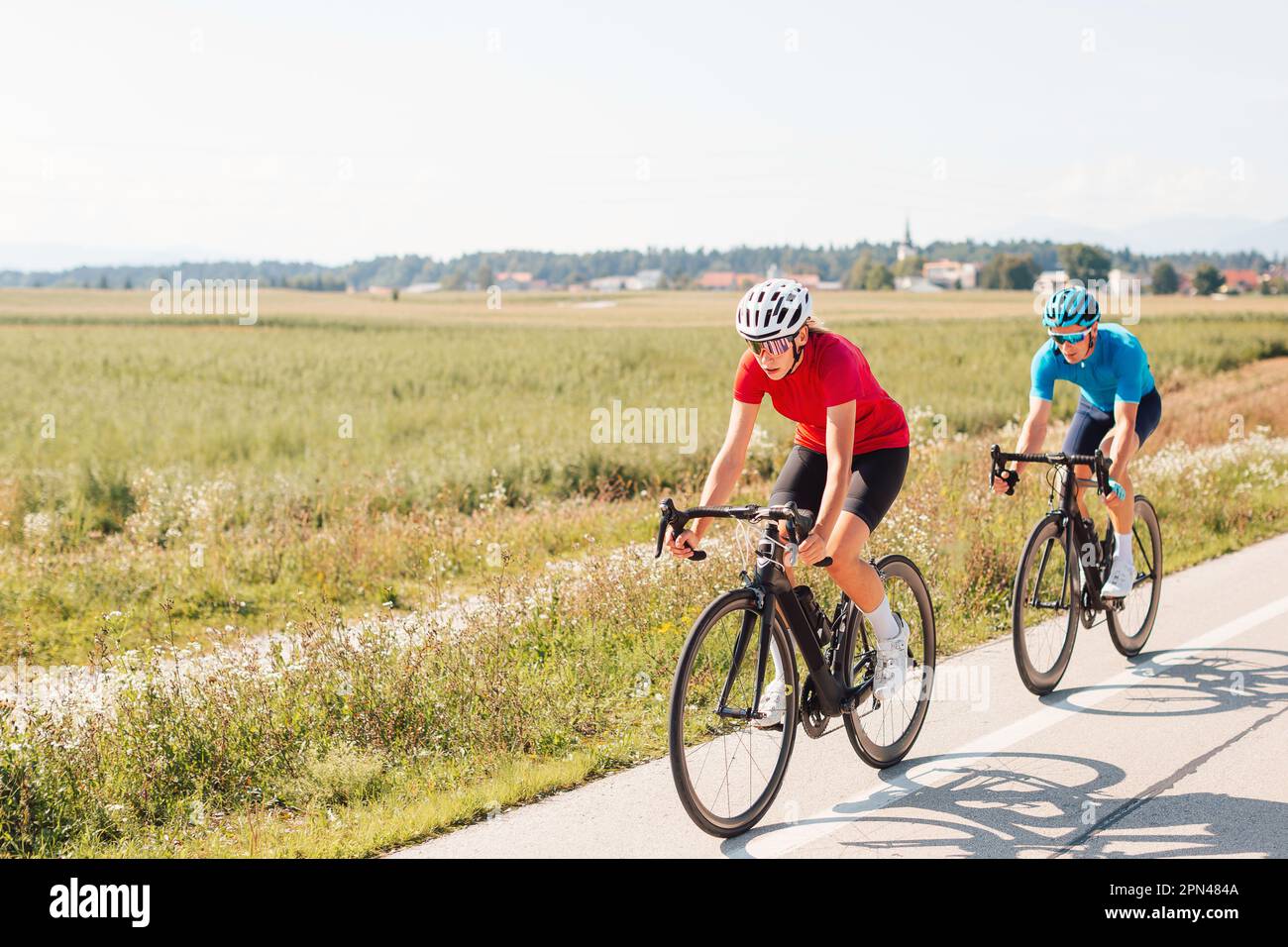 Female road racing cyclists in professional cycling wear moving in a ...