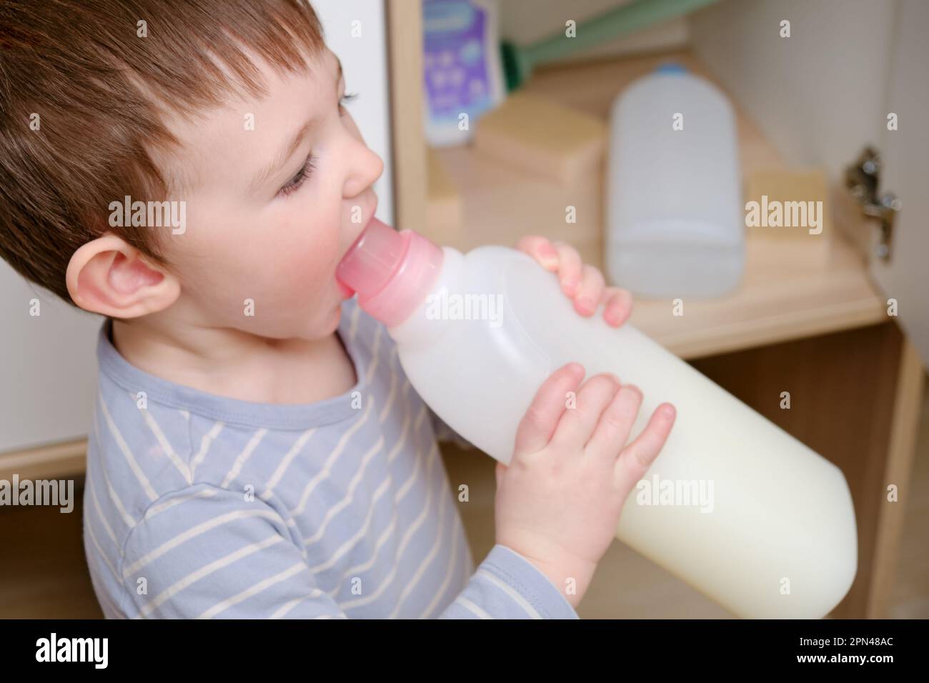 Toddler baby plays with household chemicals and detergent from the