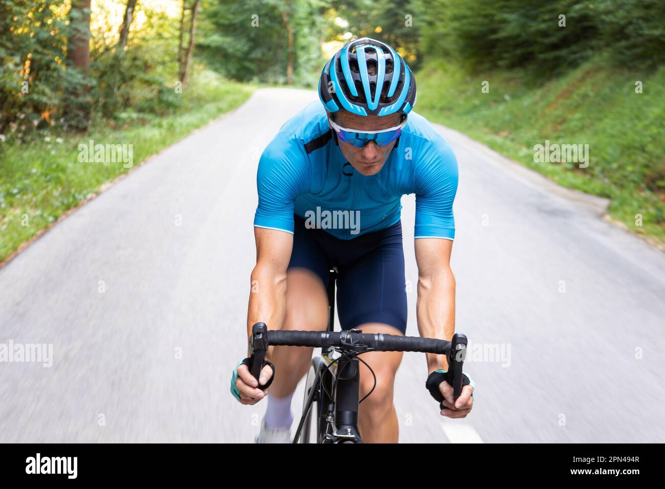 Man pedaling on a racing bike downhill in body position with straight