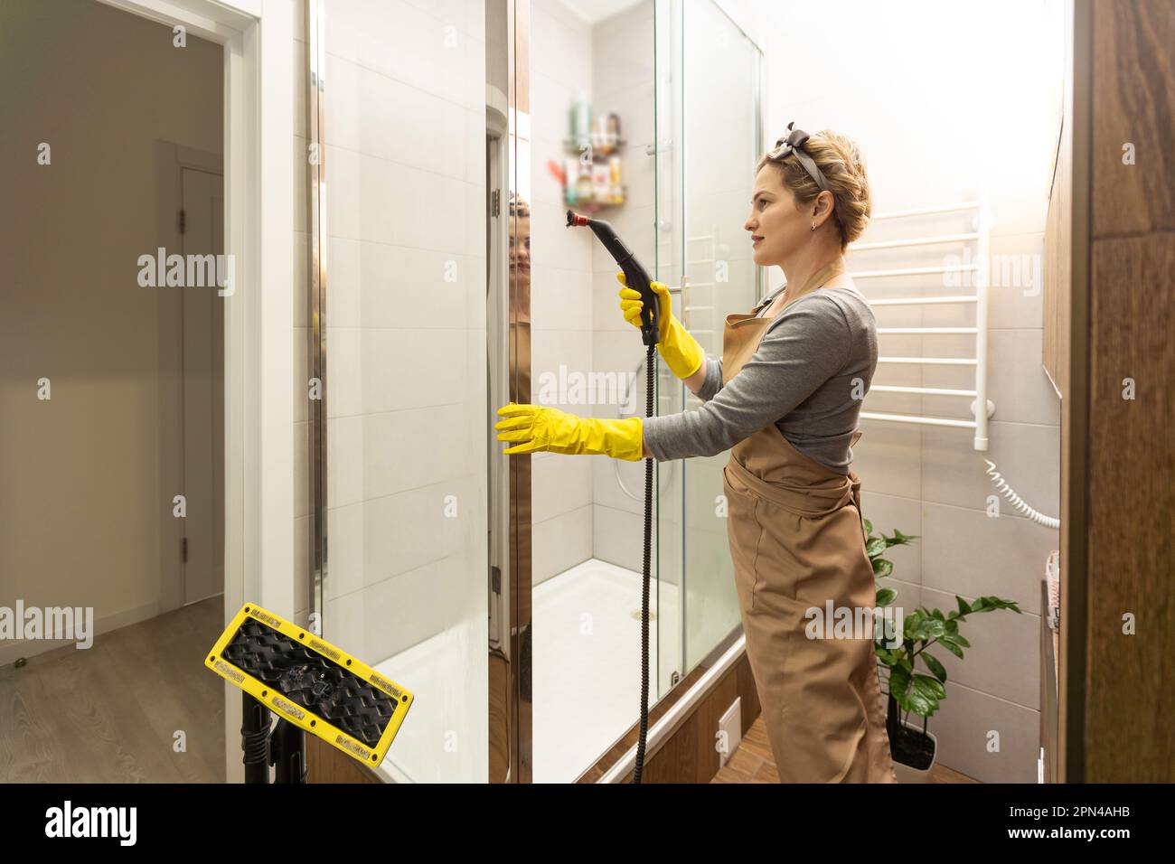 Woman doing bathroom cleaning at home, female washing tile wall with