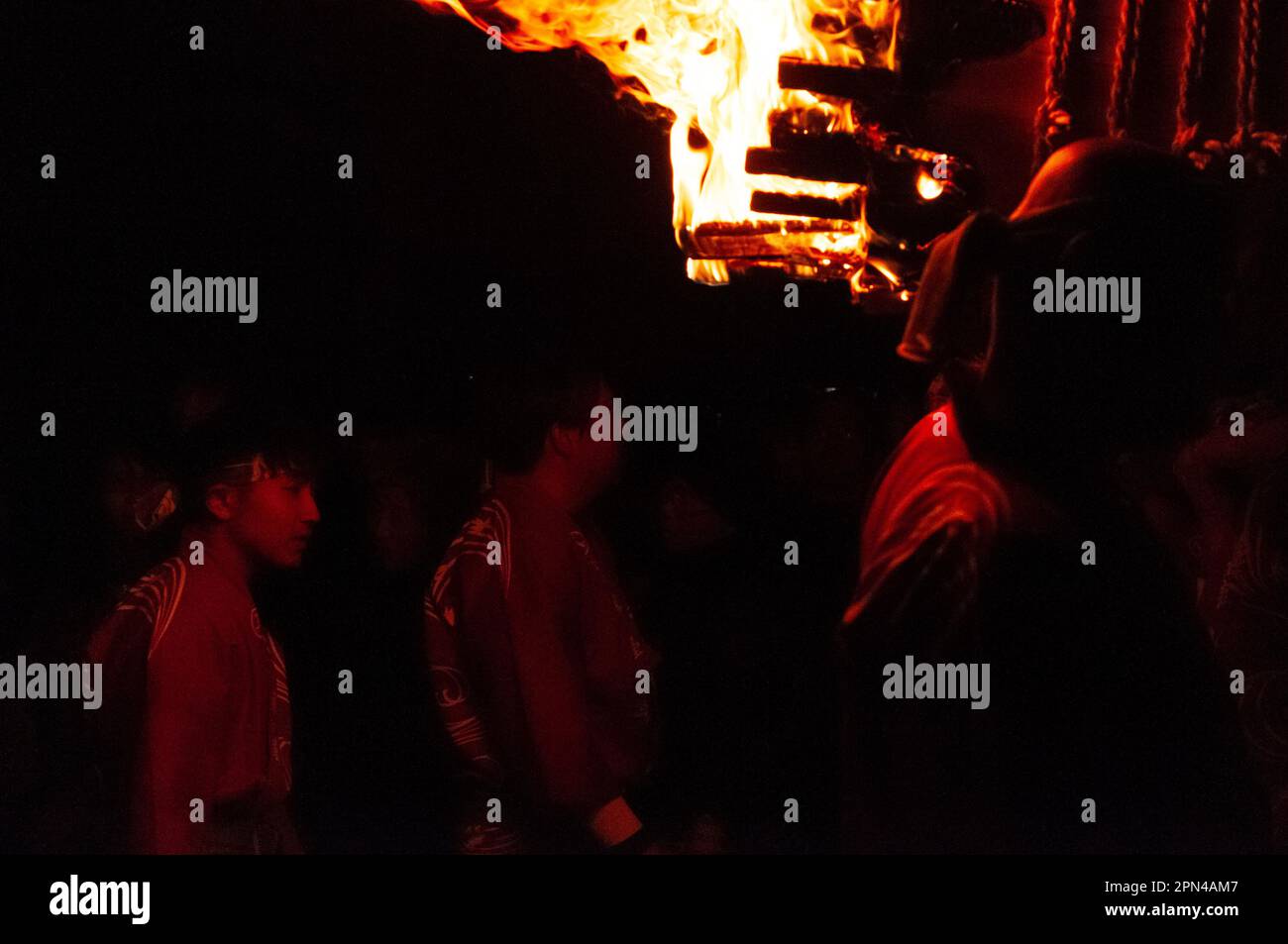 Miyajima, Japan - December 31, 2019. Participants of the Chinkasai Fire Festival at Itsukushima Shrine, near Hiroshima, carry large burning torches around the sea shore as part of a ritual to safeguard the island from fires. Stock Photo