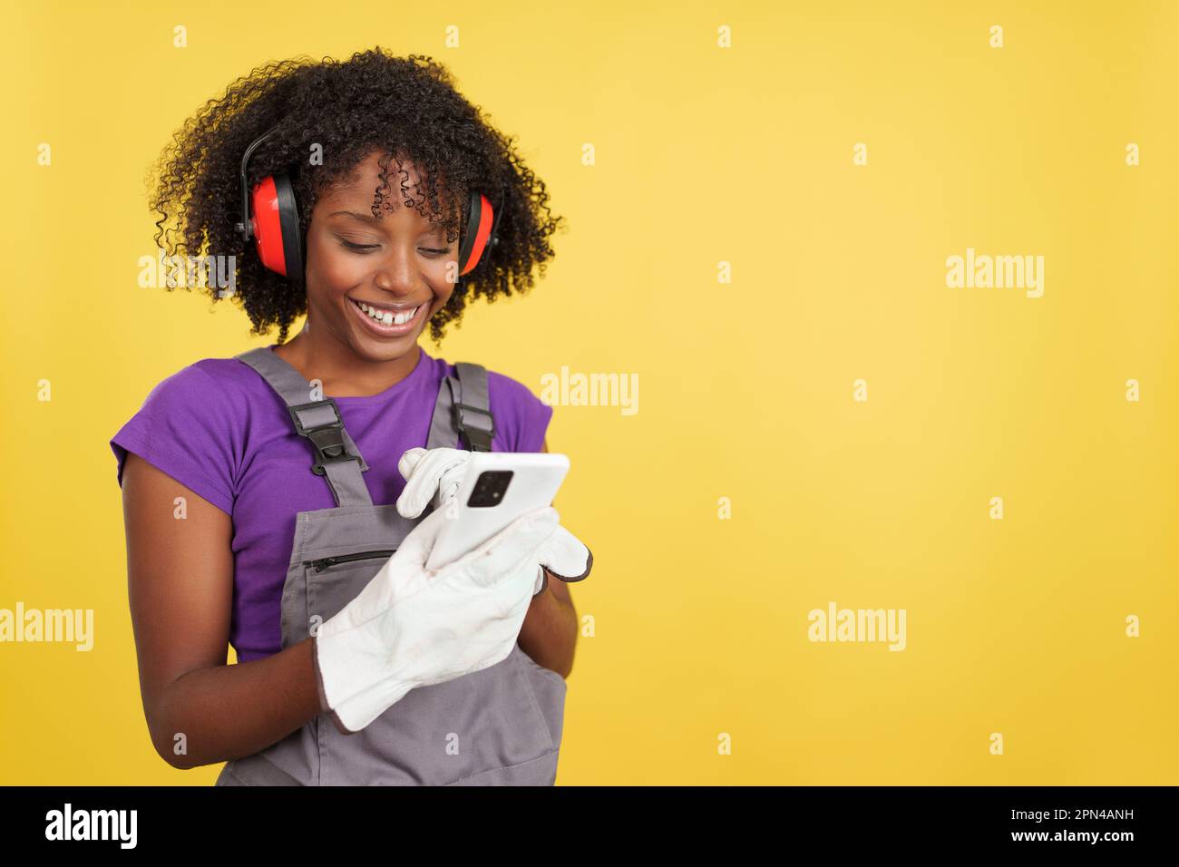 Afro female carpenter standing using the mobile Stock Photo