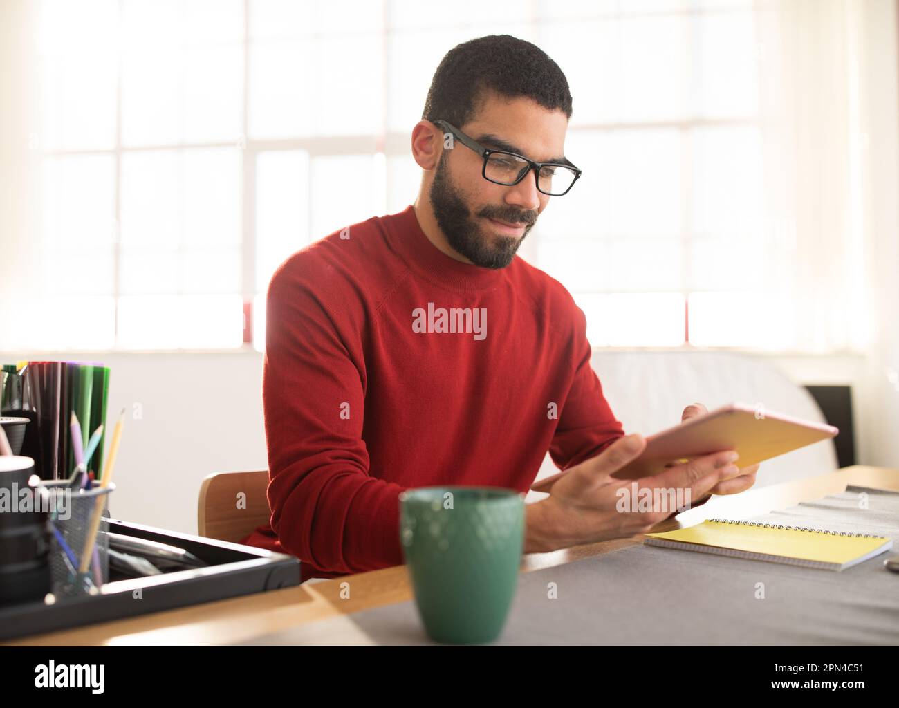 handsome hispanic man wearing eyeglasses using digital tablet at office Stock Photo