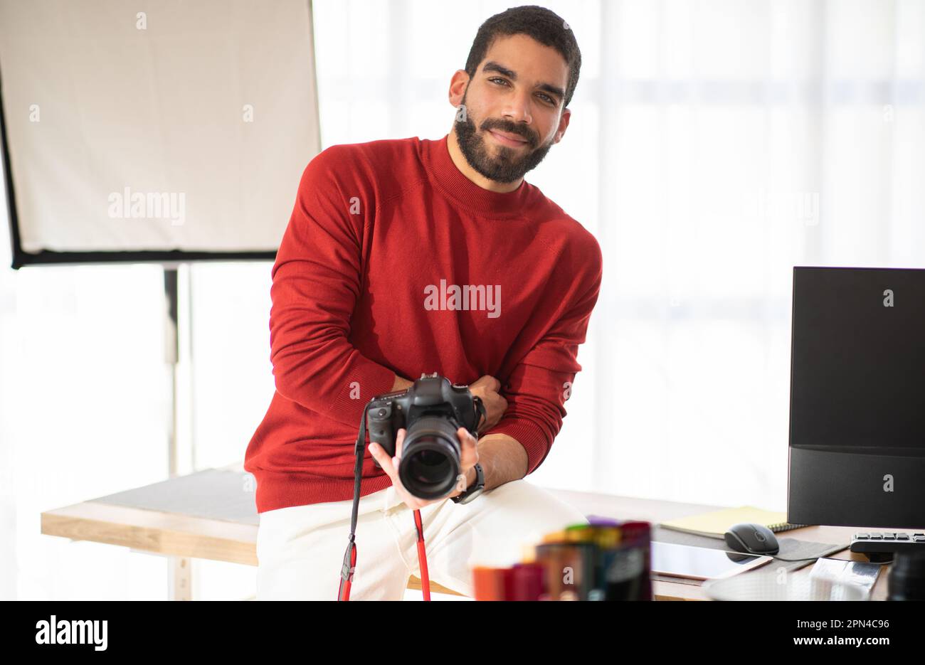 Positive young guy professional photographer posing at his workplace Stock Photo