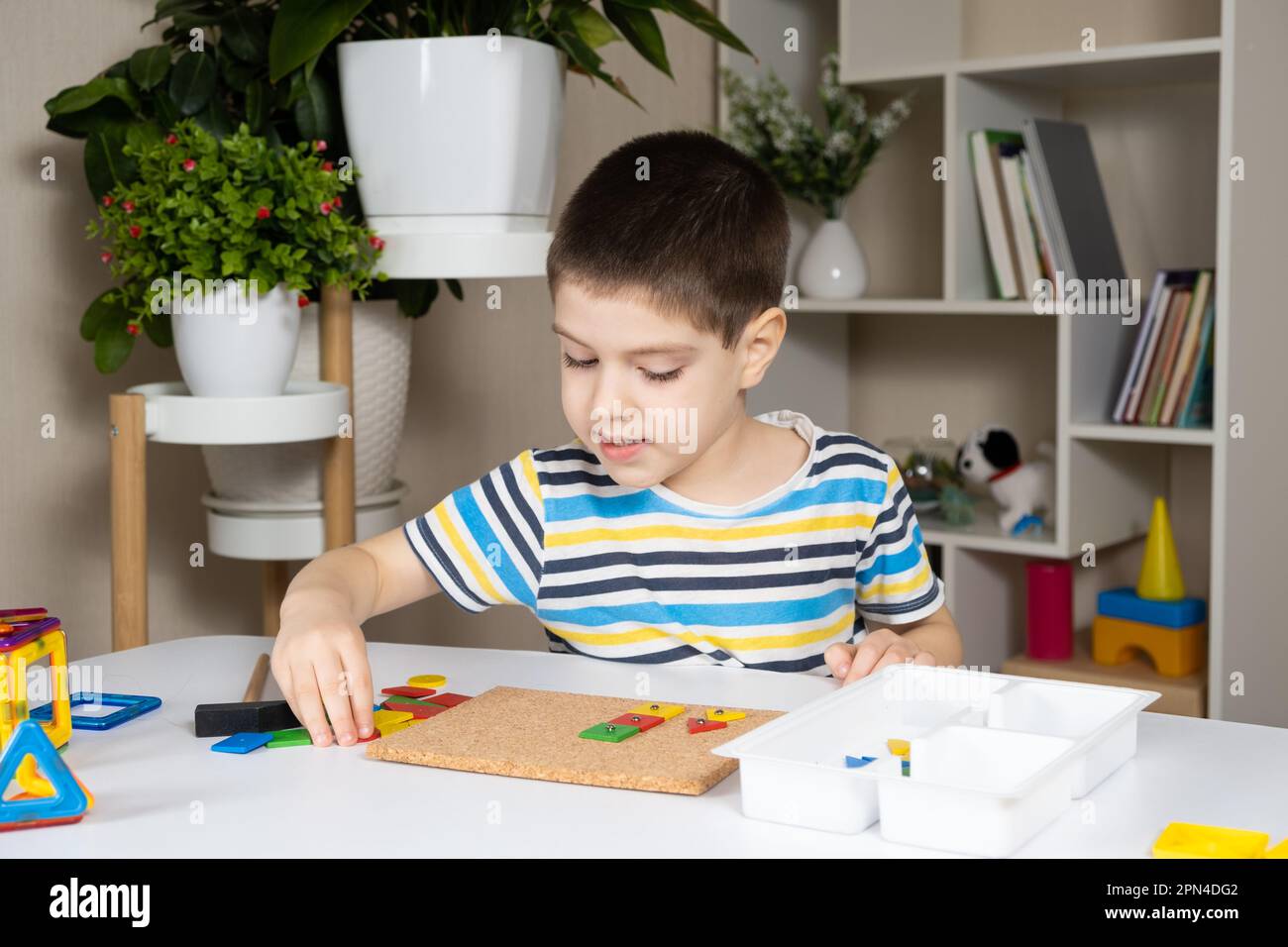 A preschool child plays with a mosaic, builds figures on a board