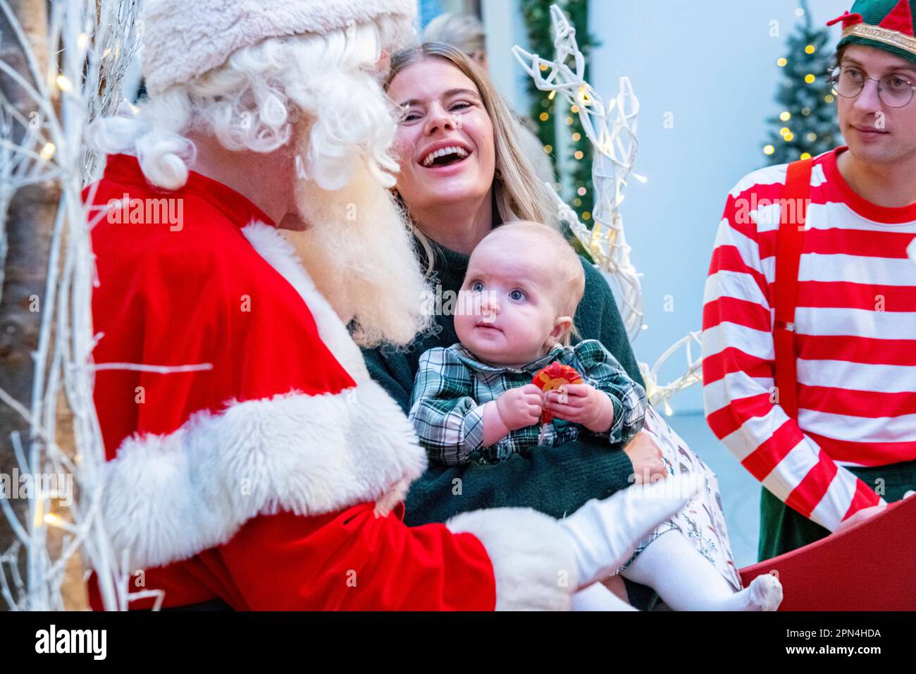 Father Christmas and an elf looking majestic with a mother and daugher in a winter setting Stock Photo