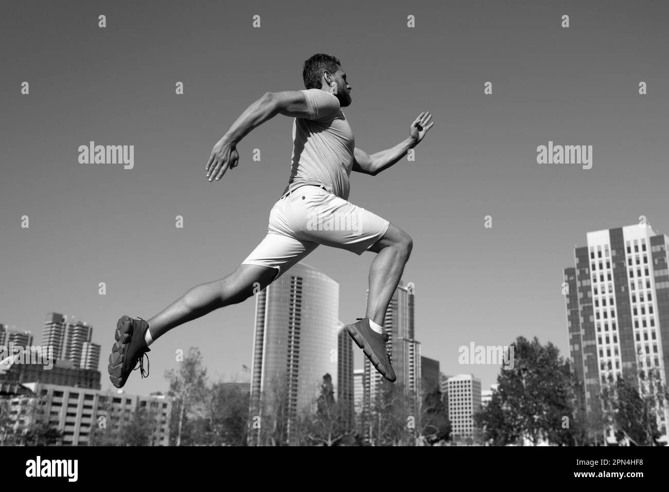 Athletic young man running in city. Dynamic jumping movement. Young and active jogger running. Urban sport concept. Stock Photo