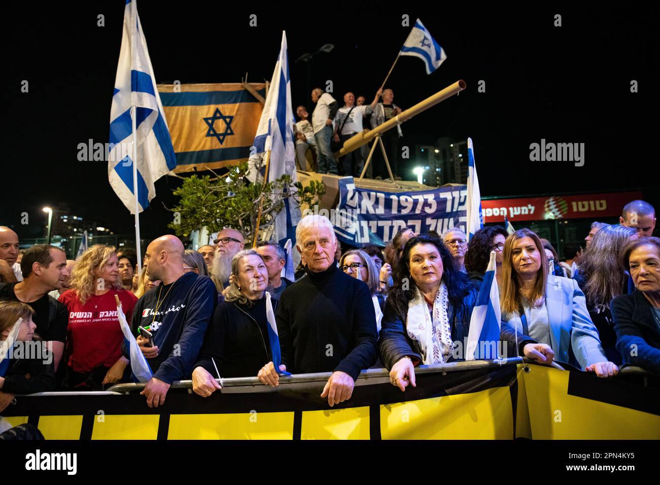 Israel. 15th Apr, 2023. Israeli protestors against the reform stand in front of a tank model brought by the warriors of the 73' Yom Kippur War as they wave an authentic old Israeli flag used at the battle in a protestation against the legal overhaul in Netanya. Apr 15th 2023. (Matan Golan/Sipa USA). Credit: Sipa USA/Alamy Live News Stock Photo