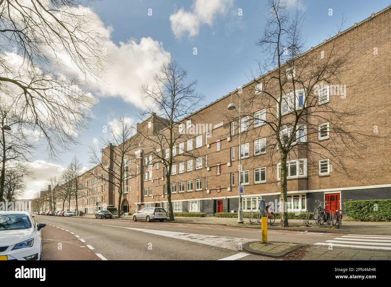 a city street with cars parked on the side of the road and trees in ...