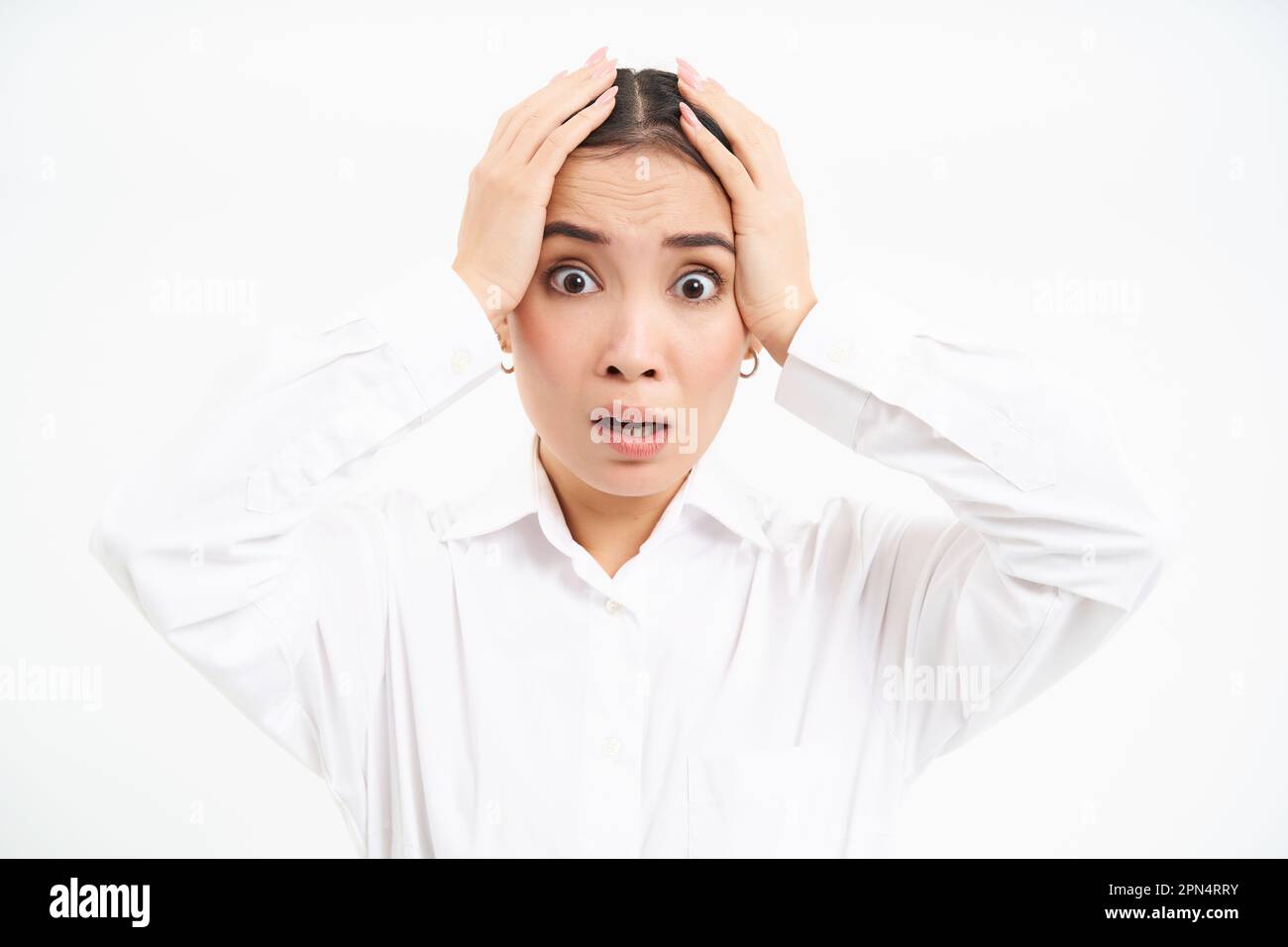 Portrait of anxious and worried asian businesswoman grabs head in hands, panics, looks nervous