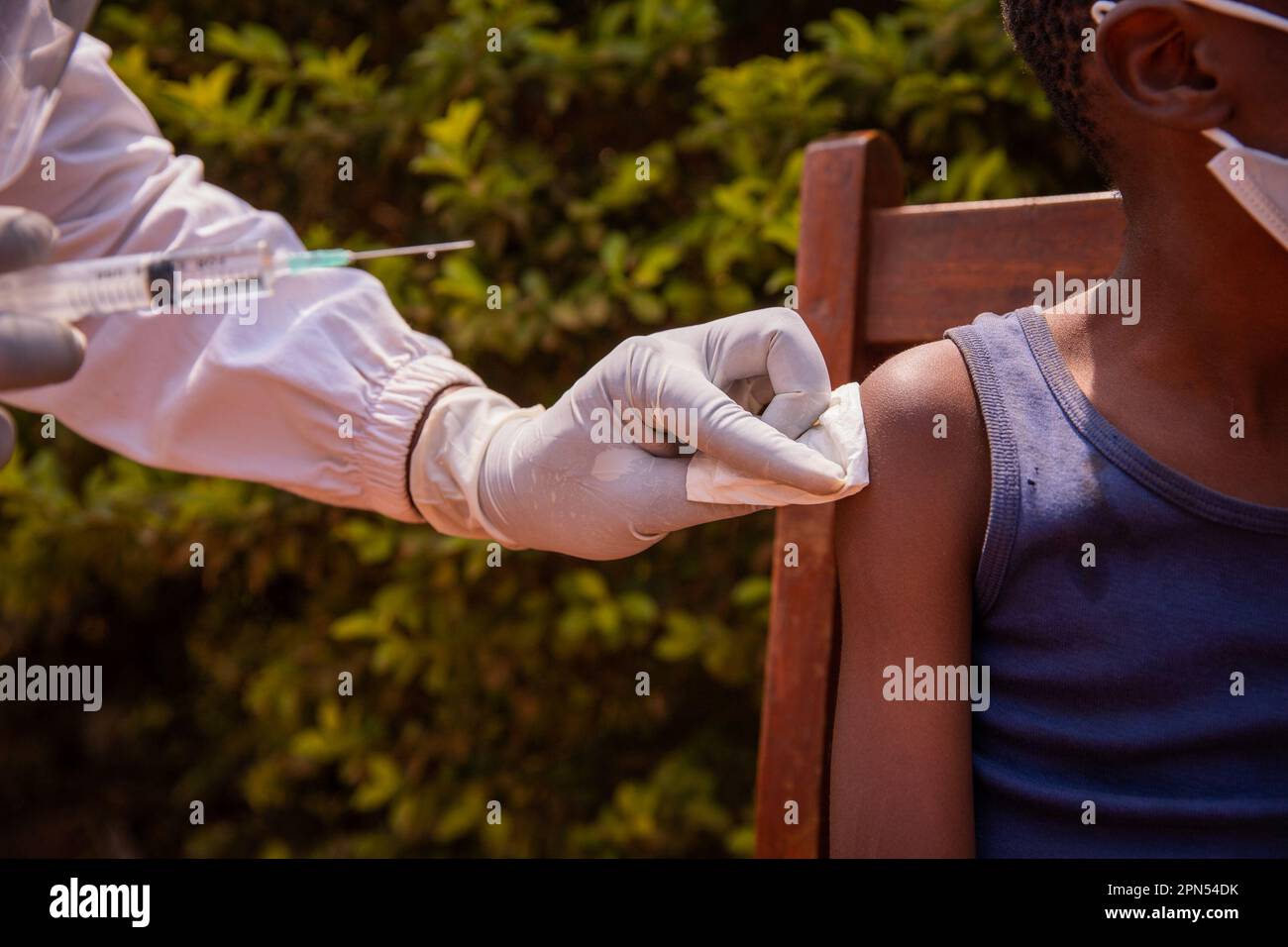 Close up of a doctor's hands holding the syringe and vaccinating a child in Africa. Stock Photo