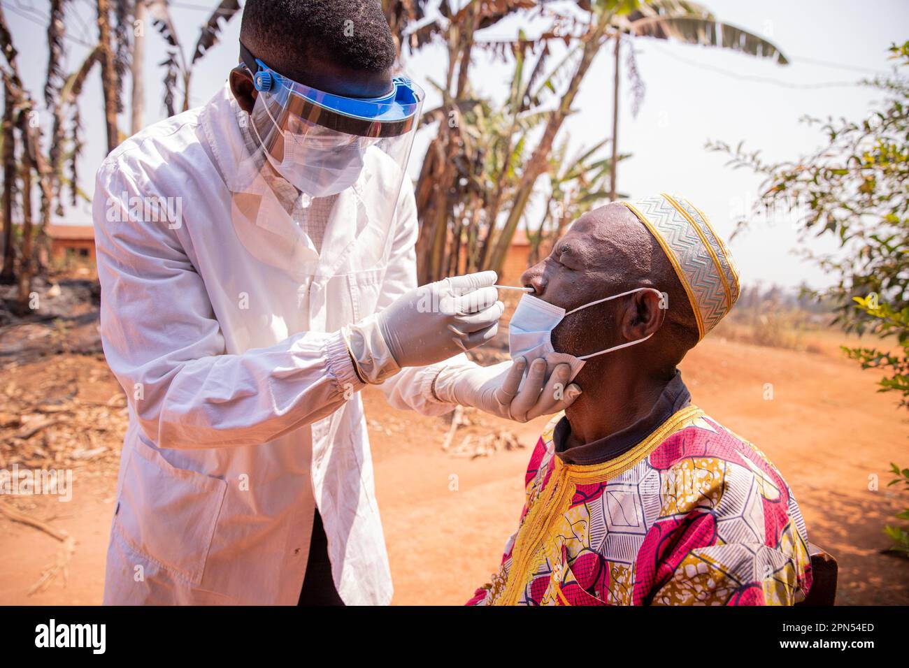 An African doctor performs a nasal swab test on an elderly patient. Stock Photo