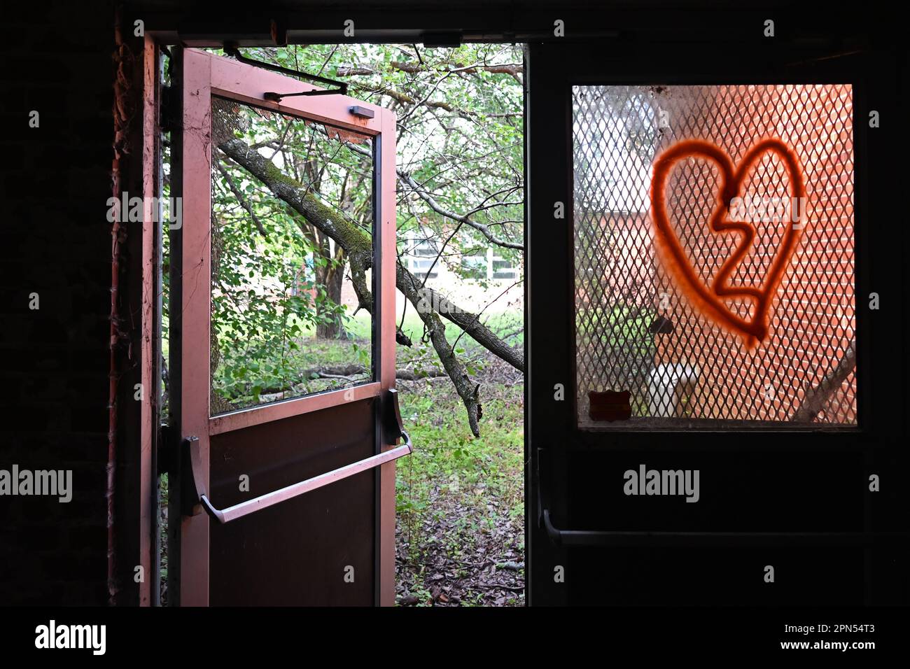 An exterior door with a broken window is propped open at a school abandoned since 2001. Stock Photo
