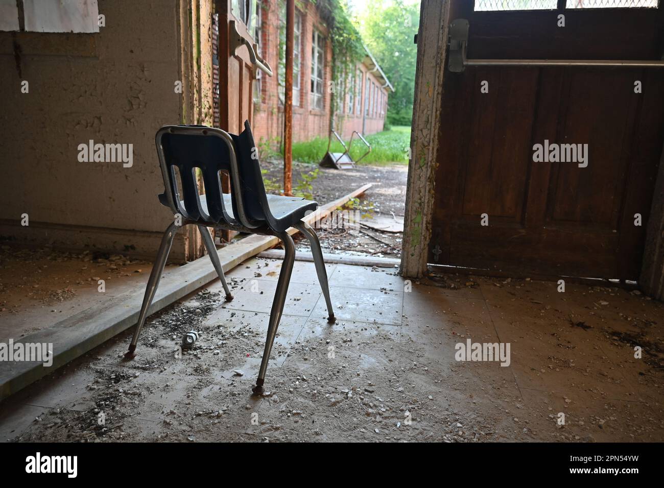 A discarded student desk left in front of an open door at a school abandoned since 2001. Stock Photo
