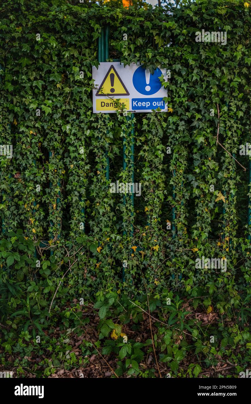 Warning signs,  Signage being  obscured by greenery Stock Photo