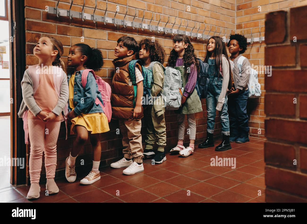 Primary school students waiting in line outside their classroom. Group of children eagerly waiting to start class in the morning. Elementary age kids Stock Photo