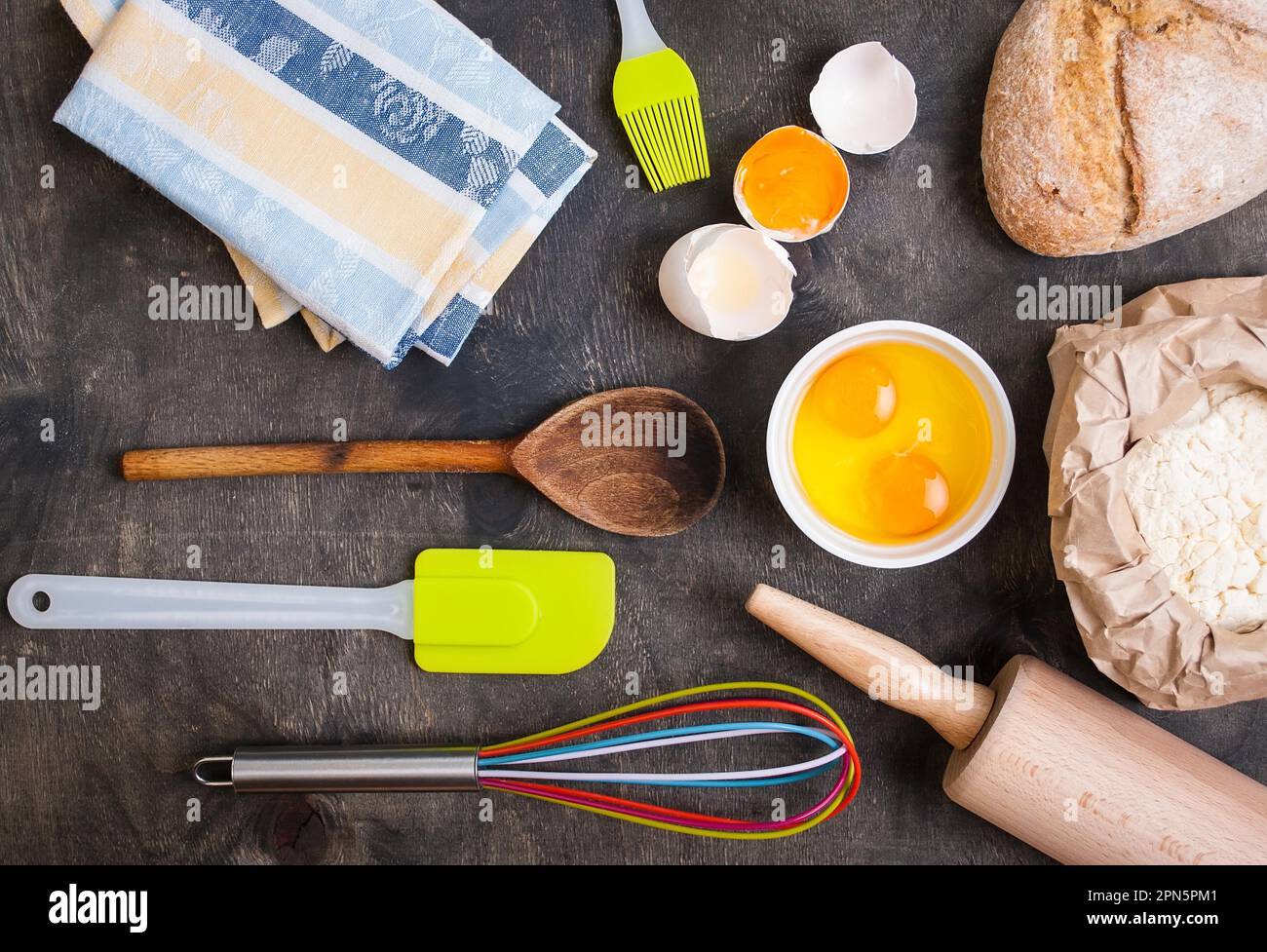 Baking dark background with utensils, napkin, eggshell, bread, flour ...