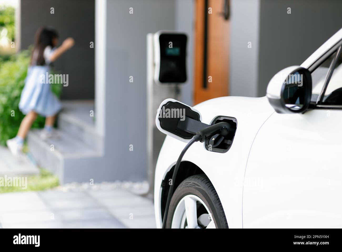 Focus EV car recharging battery at home charging station with blurred