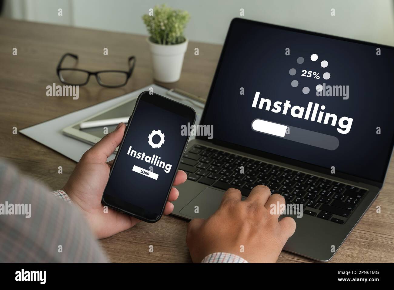 man installing Software Update On Mobile Phone And Laptop digital technology communication Stock Photo