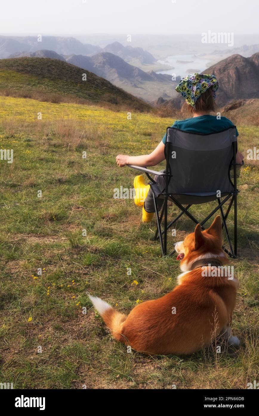 A girl with a Pembroke Welsh Corgi dog admire the beautiful landscape ...