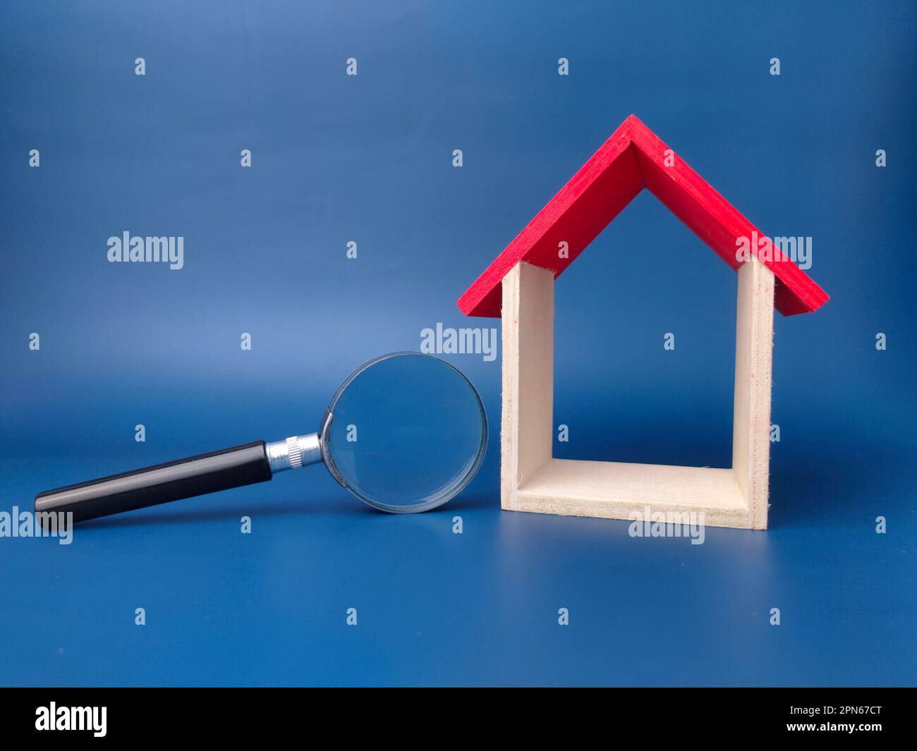 Toy house and magnifying glass on a blue background Stock Photo
