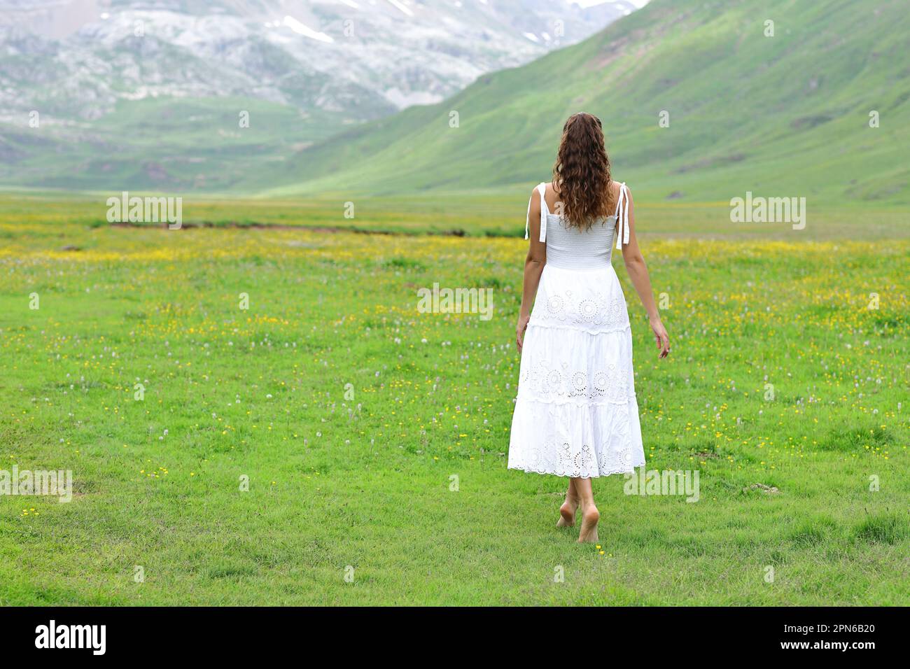 Back view of a woman in white dress walking in nature Stock Photo