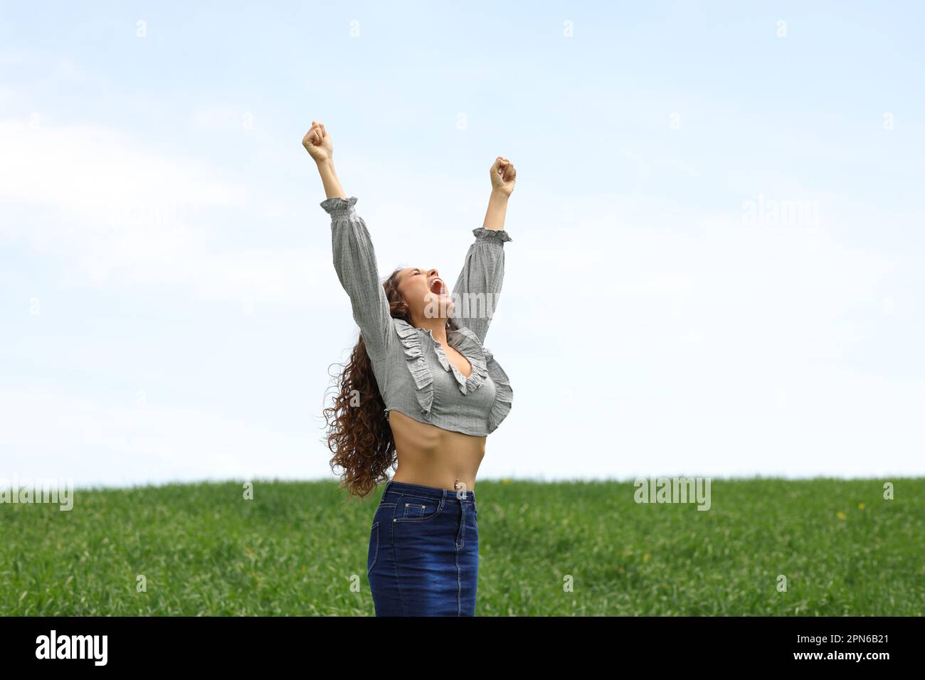 Excited woman raising arms celebrating in a field Stock Photo - Alamy