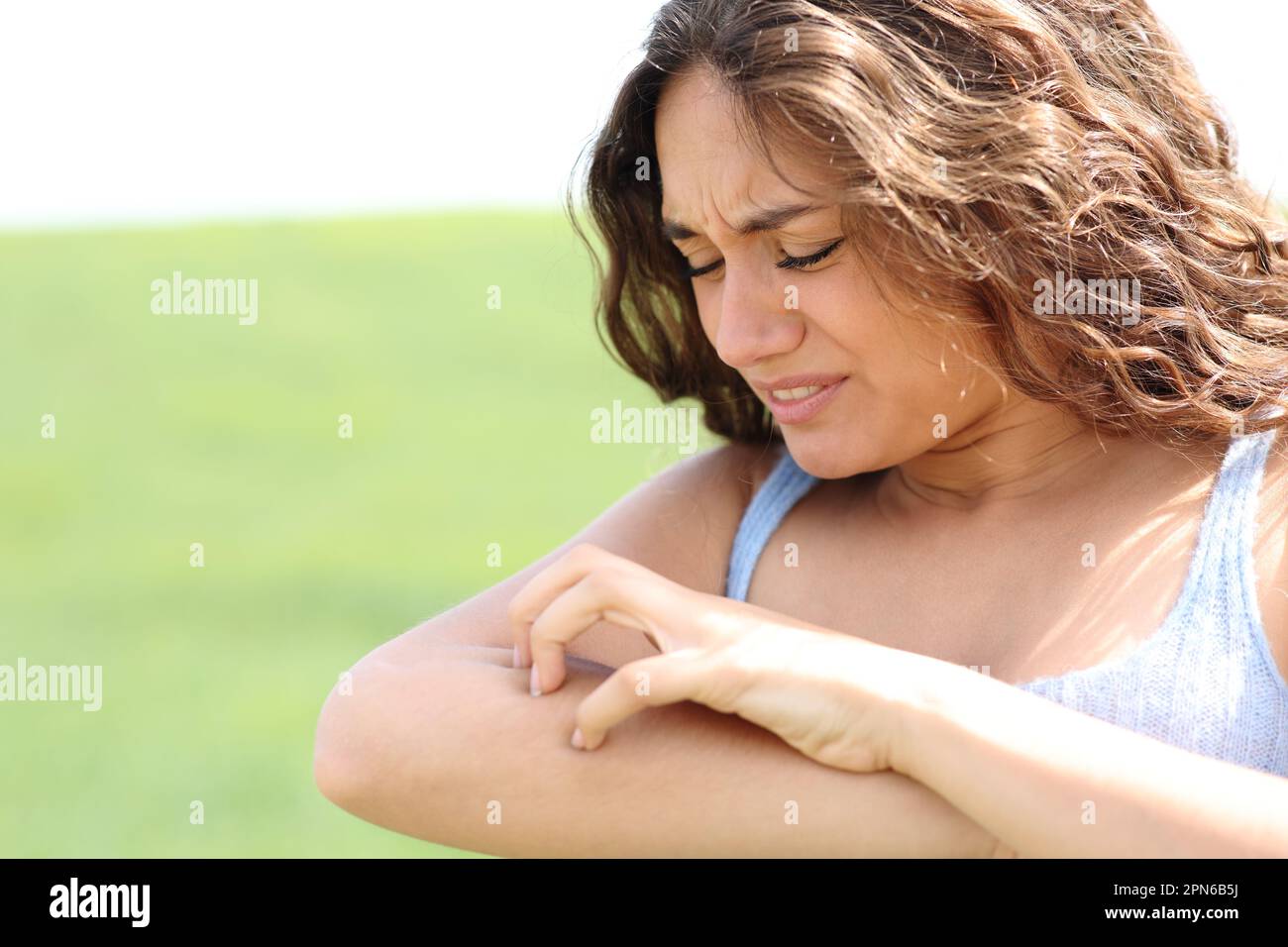 Woman scratching itchy arm in a field Stock Photo