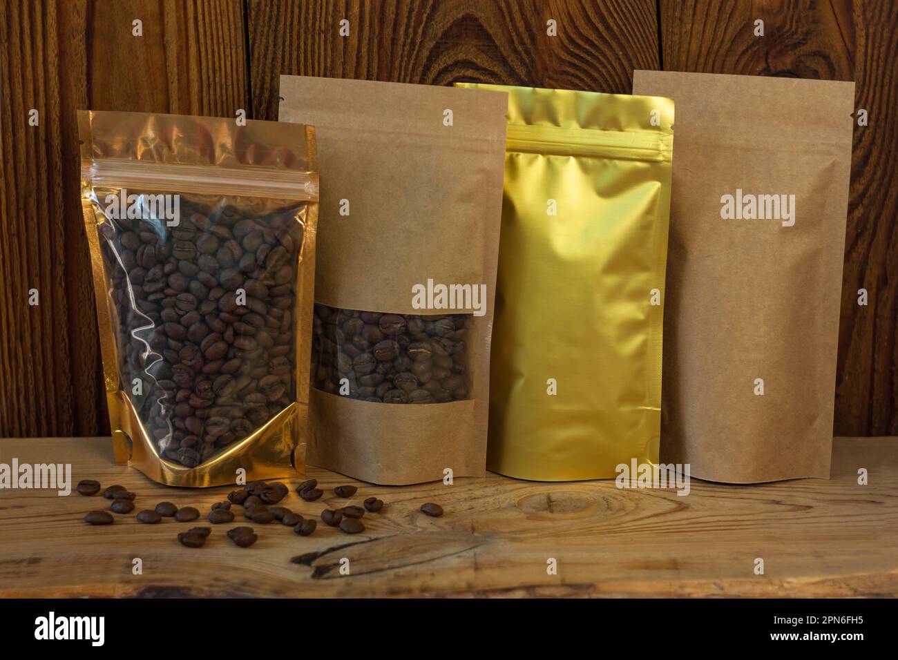 Brown kraft paper and golden metallized pouch bags with coffee beans ...