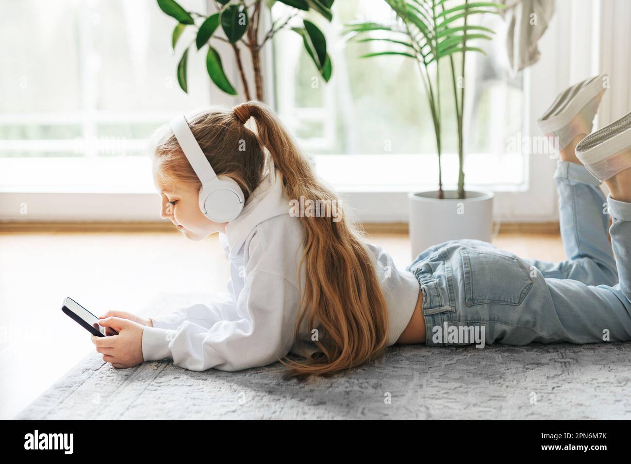 Smiling little girl listening music lying on the floor Stock Photo - Alamy
