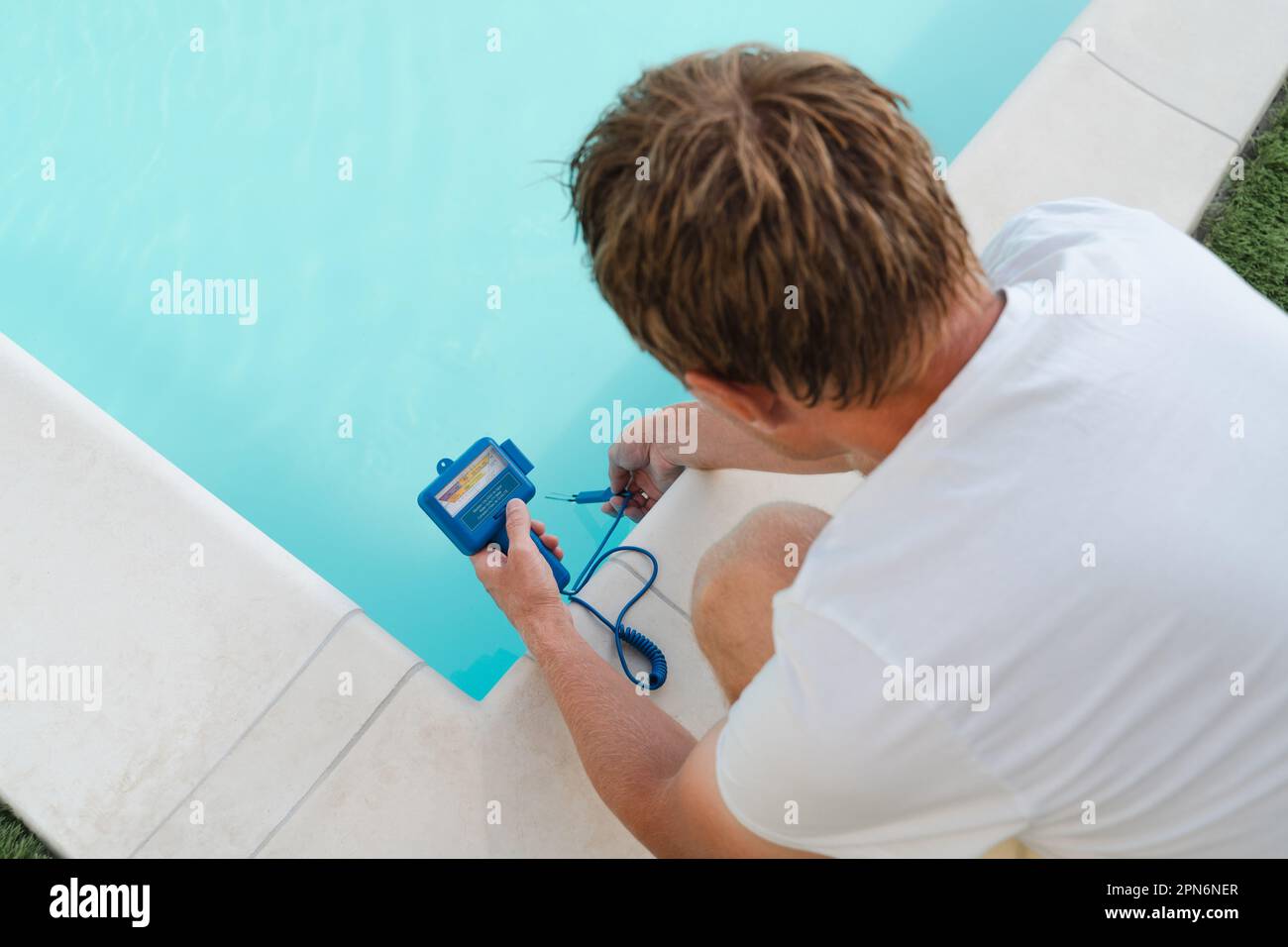 A man checks the water in the pool with a water quality meter Stock