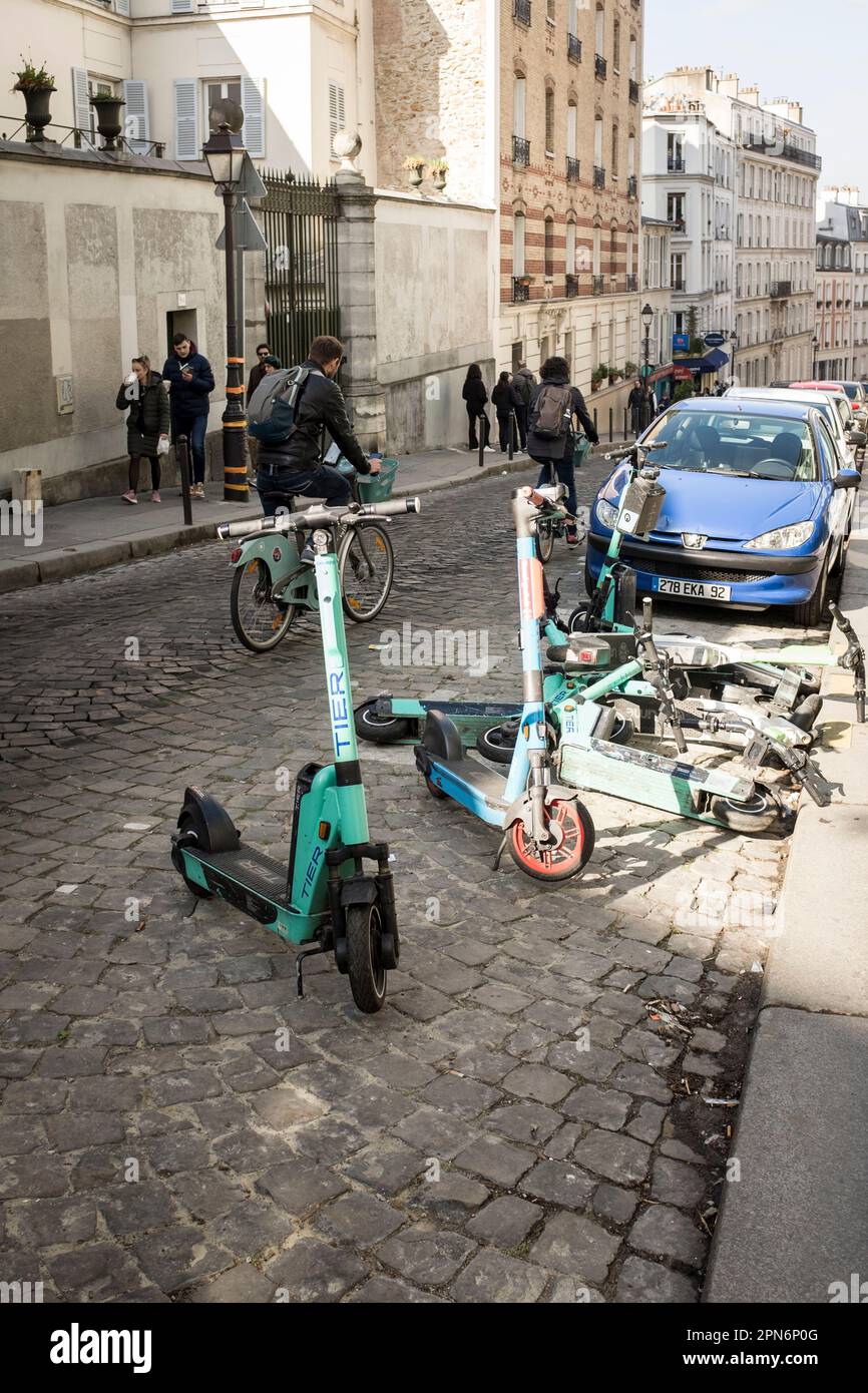 Rental E-scooters from various companies parked and fallen in the narrow streets of Montmartre, Paris, France. Stock Photo