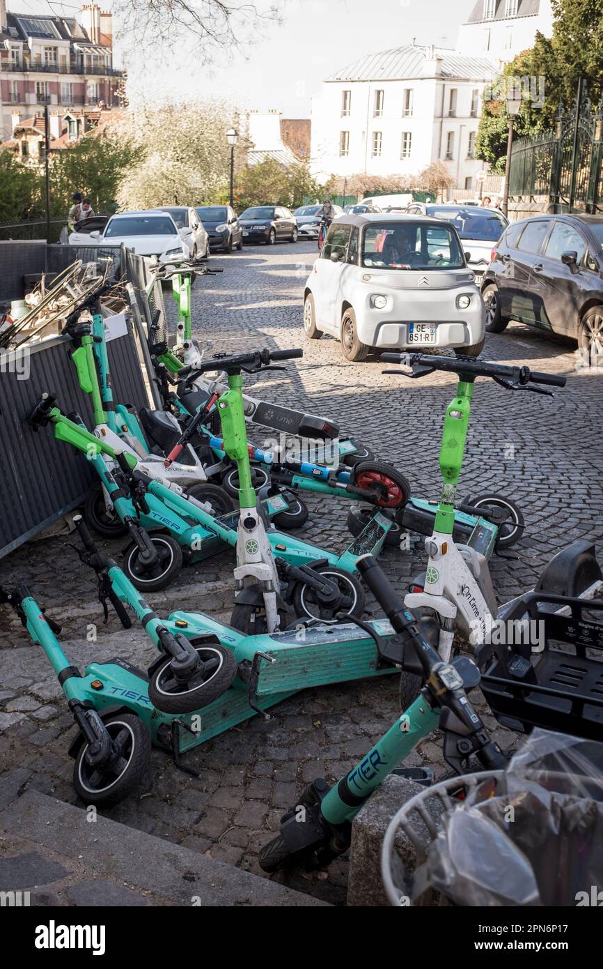 Rental E-scooters from various companies parked and fallen on a street in Montmartre, Paris, France. Stock Photo