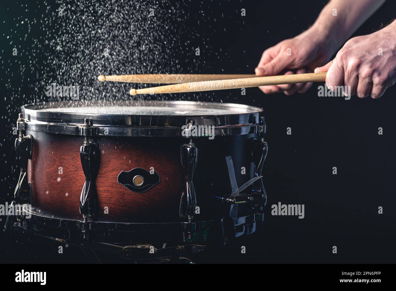 Drummer using drum sticks hitting snare drum with splashing water Stock