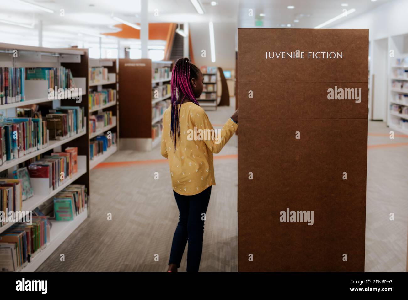Young black girl looking at books in a library Stock Photo