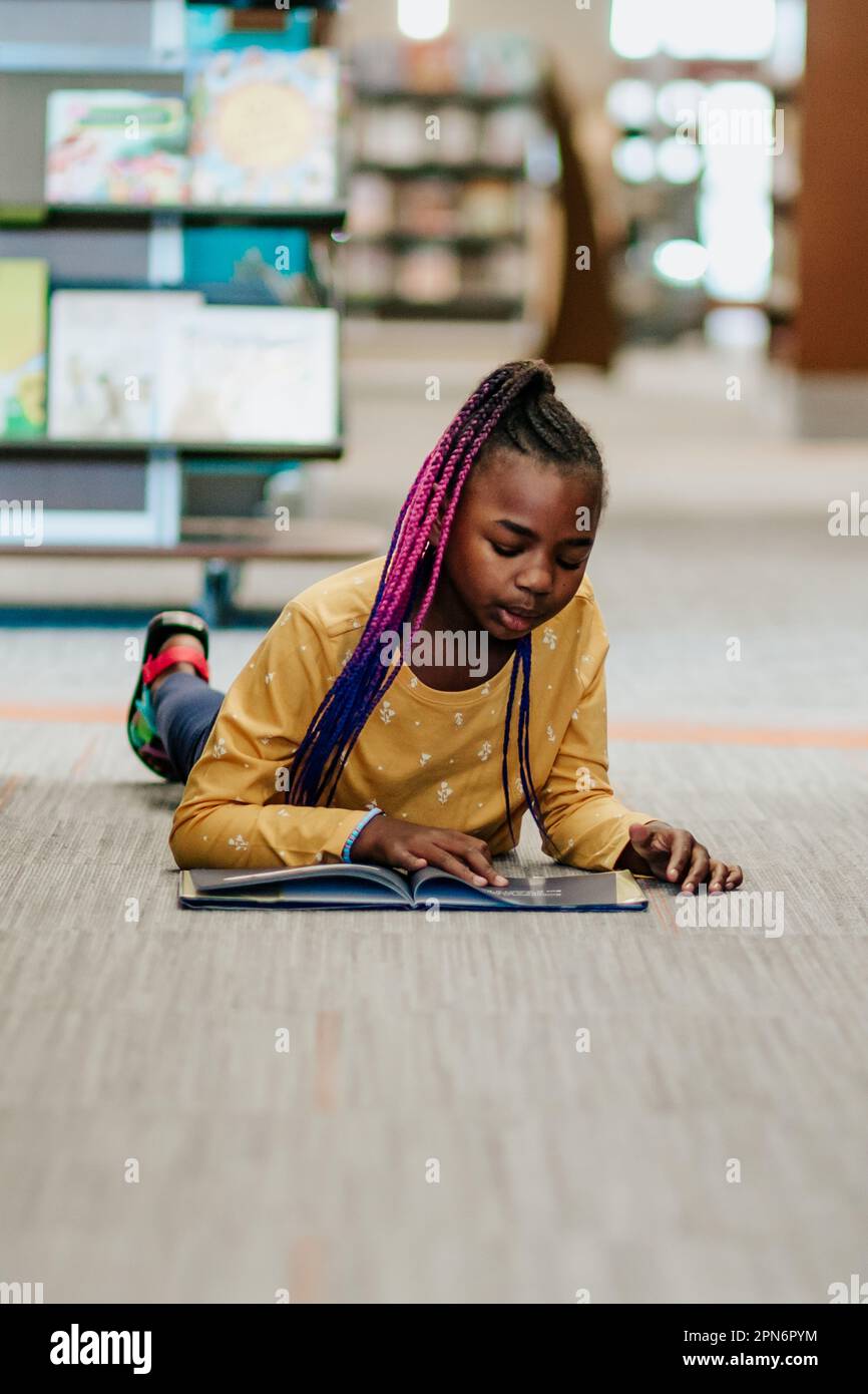 Young girl reading alone in library Stock Photo