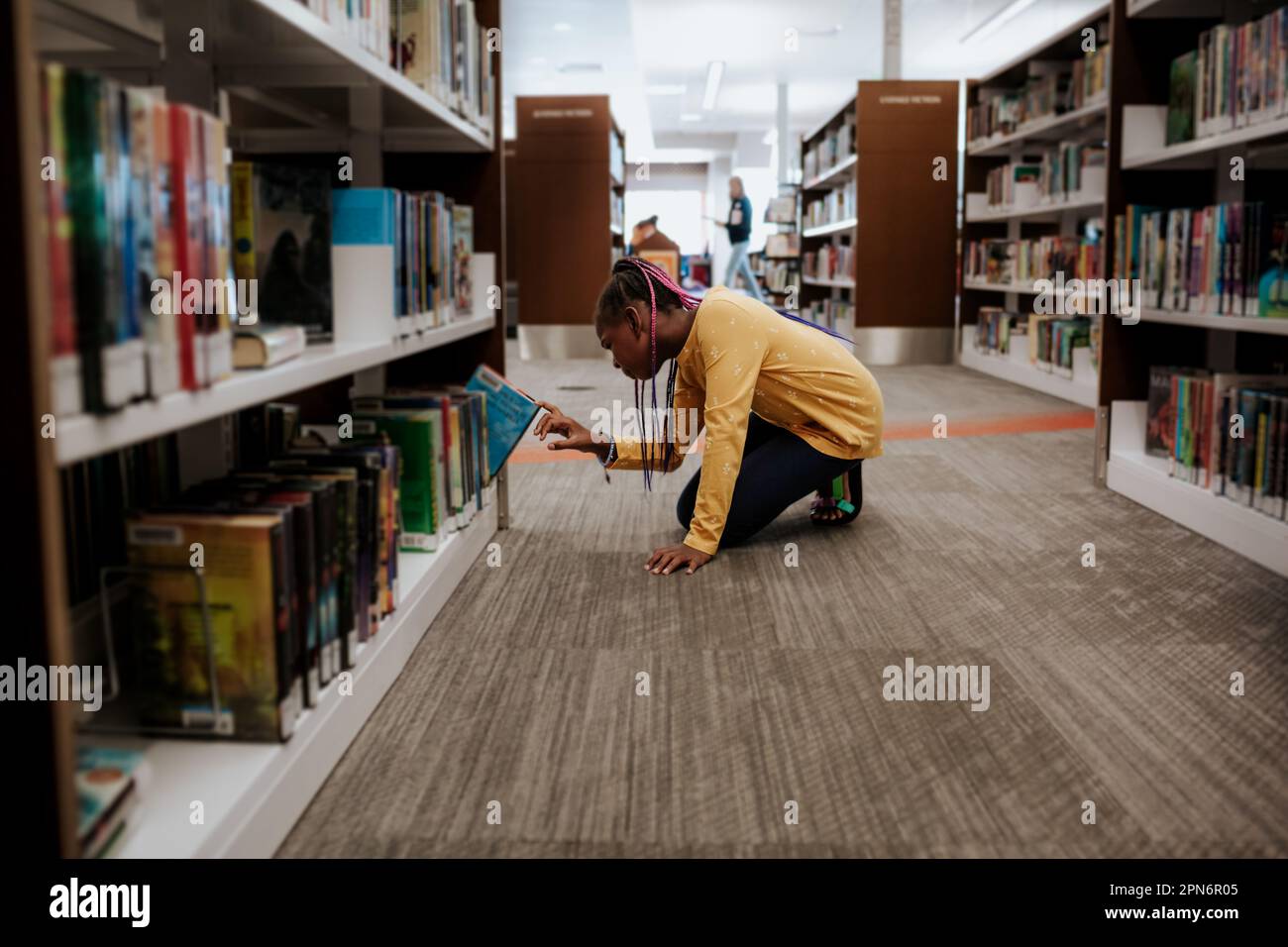 Young girl choosing book in library Stock Photo