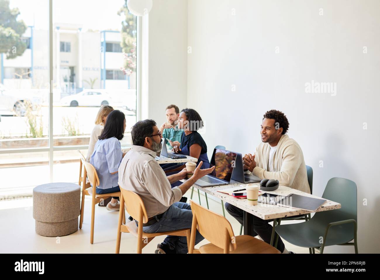 Multiracial colleagues discussing while sitting in coffee shop Stock Photo