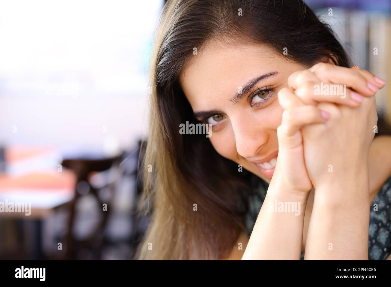 Timid woman looking at you sitting in a restaurant Stock Photo