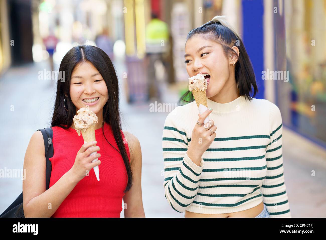 Smiling Asian girlfriends eating ice cream Stock Photo