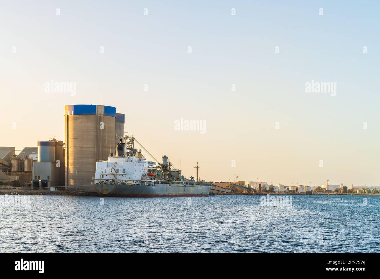 Commercial cement carrier at Port Adelaide docks viewed across the Port River at sunset, South Australia Stock Photo