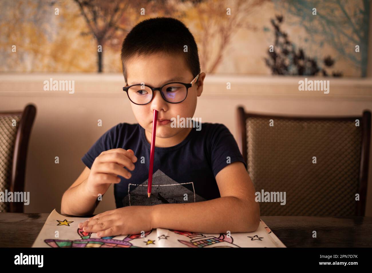 A bored little boy student inserted a pencil into his nose. The concept of ADHD Stock Photo