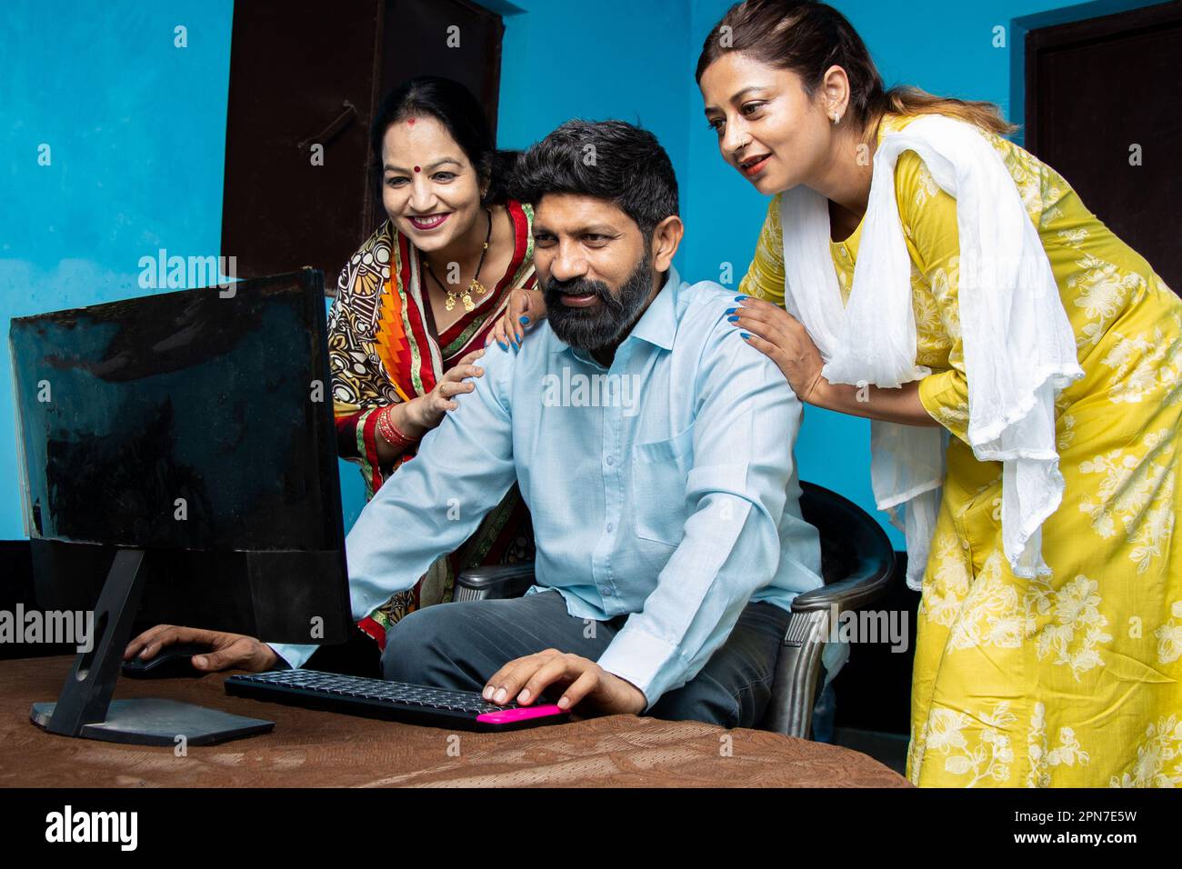 Traditional indian Man with his wife and daughter using computer. Learn ...