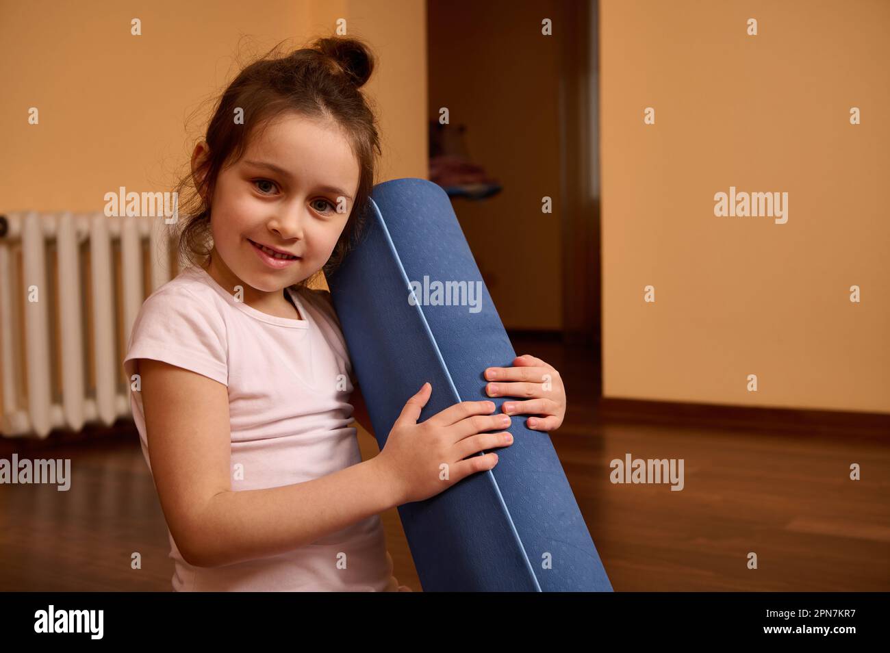 Close Up Portrait Of A Little Cute Girl Sitting On Yoga Mat