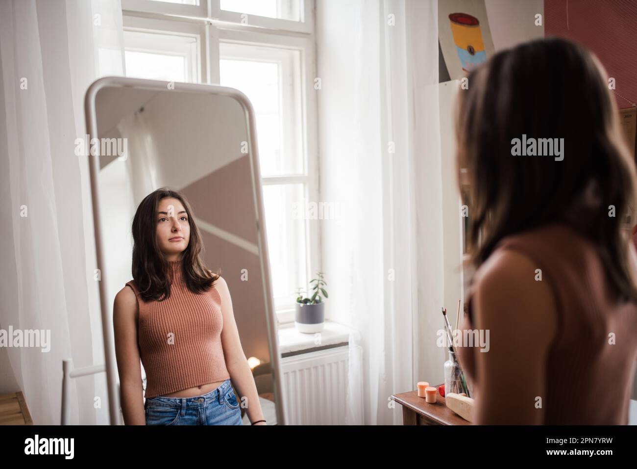 Young teenage girl looking in the mirror in her room. Stock Photo
