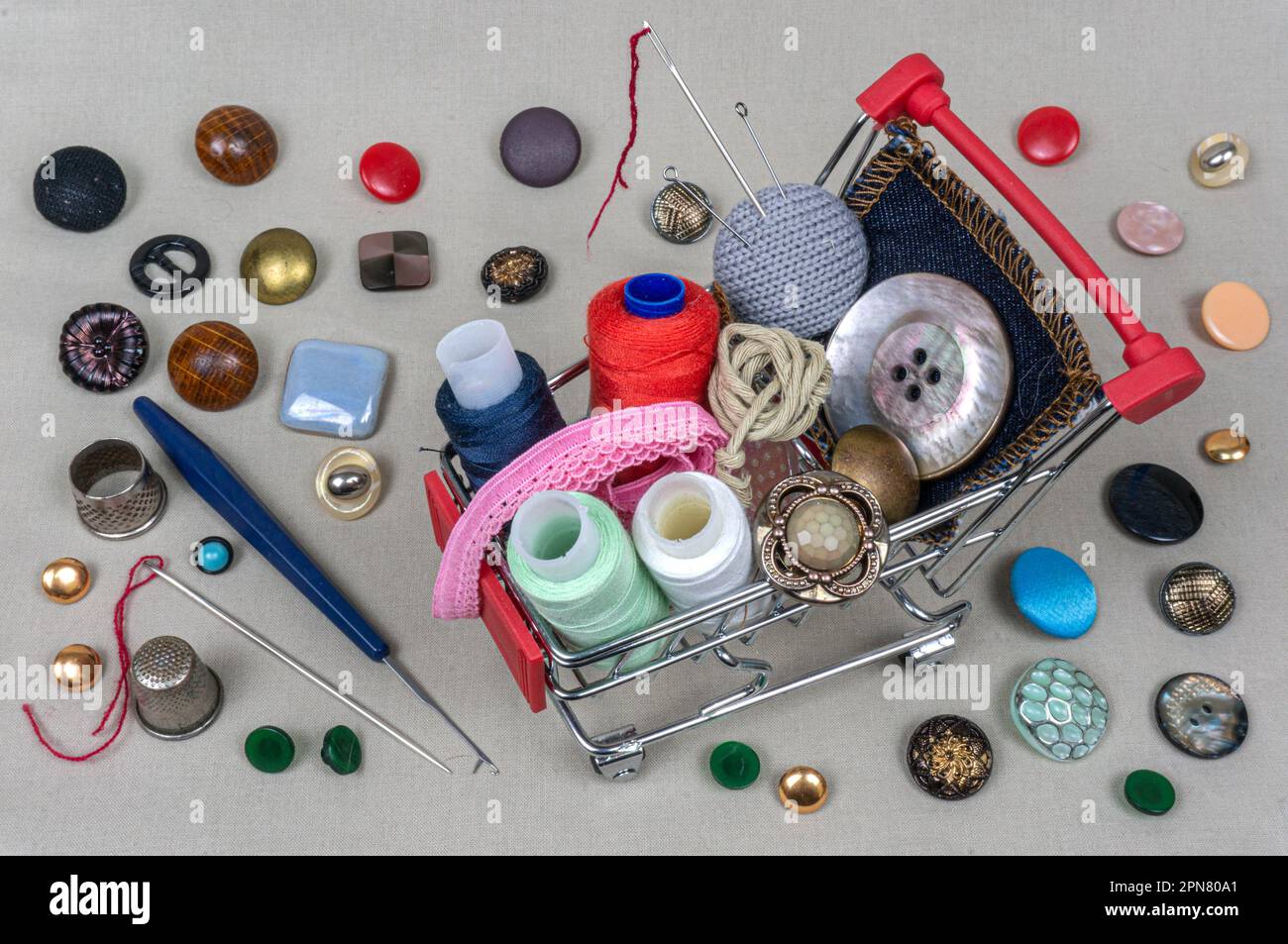 A shopping basket with threads and buttons. Next to thimbles and tools